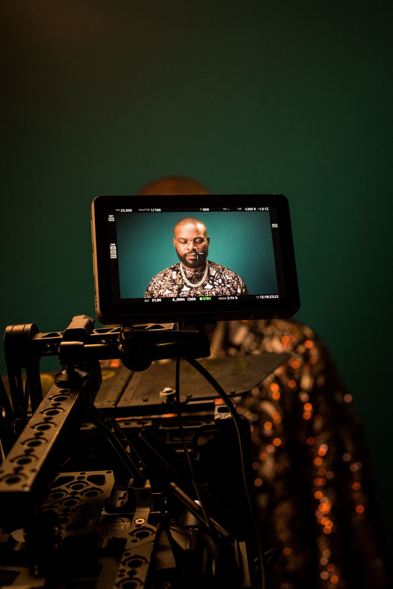 Director's monitor showing a performer on a teal backdrop during a music video or interview shoot