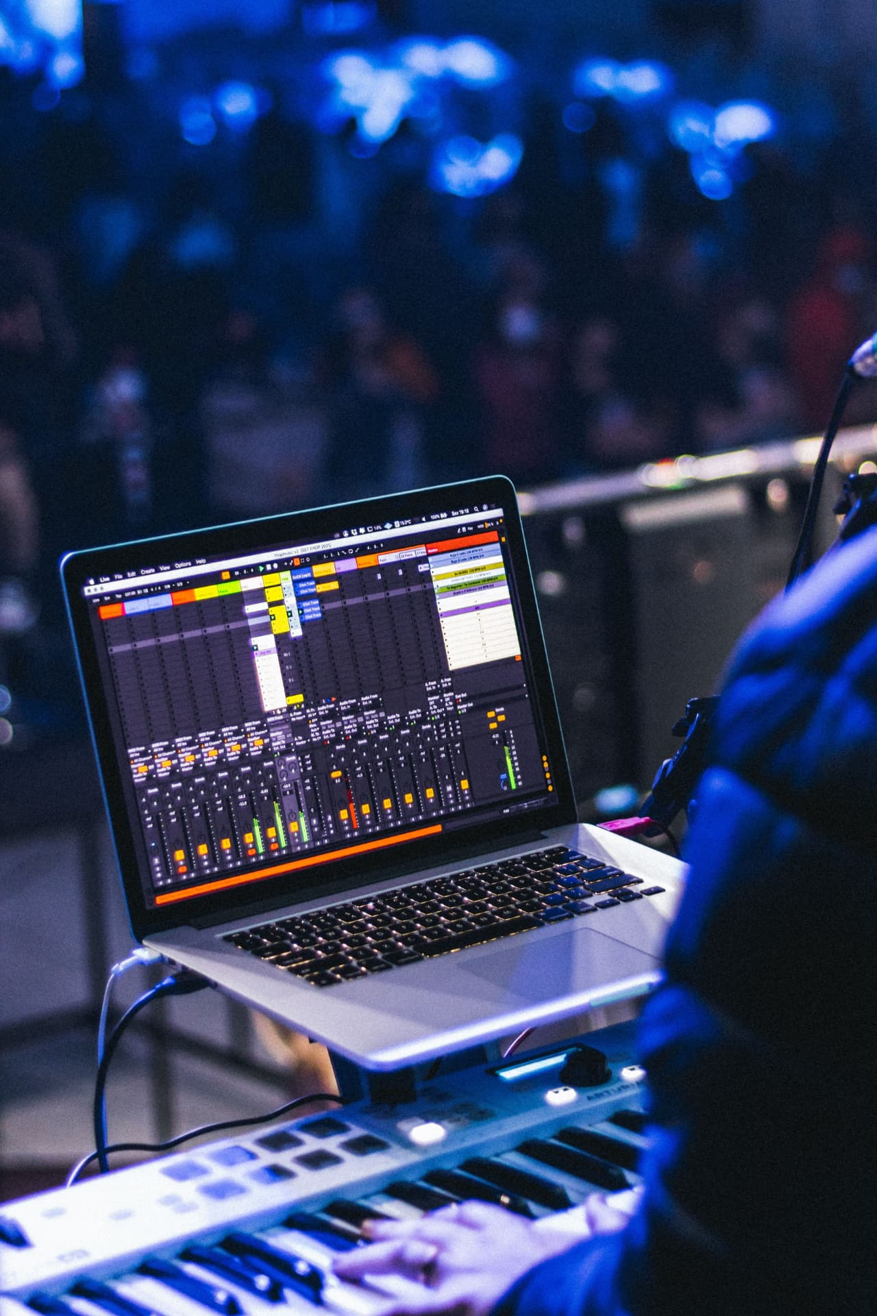 Laptop running live audio mixing software next to a MIDI controller at a concert venue